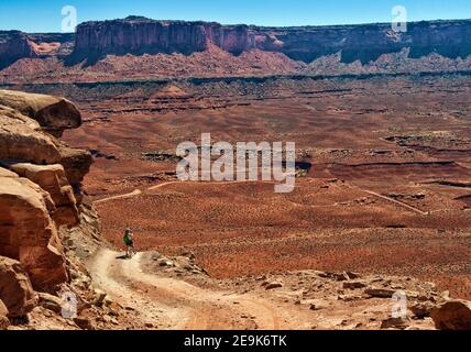 Motard de montagne Woman sur White Rim Road, à Murphy Hogback, Murphy point falaises in distance, Parc national de Canyonlands, Utah, États-Unis Banque D'Images