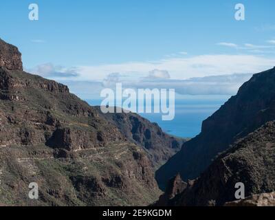 Barranco de Guayabee vue le long des ravins abruptes murs vers l'océan. Gran Canaria, île des Canaries, Espagne. Jour ensoleillé, ciel bleu, nuages blancs backgrou Banque D'Images