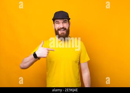 Photo d'un jeune homme barbu en chemise jaune le pointant vers lui. Banque D'Images