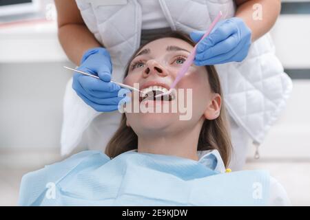 Jeune femme qui reçoit un traitement dentaire par un dentiste professionnel au clinique Banque D'Images
