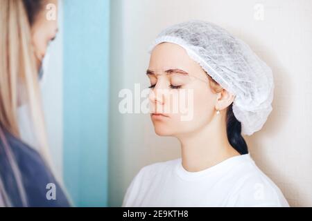 Cosmetolog beauté maître faire des marques avant la procédure permanente de maquillage Banque D'Images