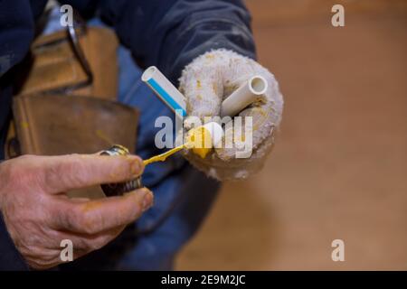 Collage des pièces d'un tuyau d'eau en pvc à l'aide de colle à ciment installation de montage tuyaux en polypropylène de plomberie pour l'eau Banque D'Images