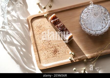 Plateau en bois avec savon fait main à base d'ingrédients naturels. Arrière-plan chaleureux avec des reflets du soleil sur le thème des cosmétiques naturels. Banque D'Images