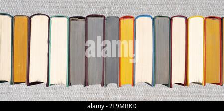 Pile de livres de couverture rigide sur la étagère. Vue rapprochée des livres à dossier rigide multicolores sur fond gris en osier. Titre de la pose plate Banque D'Images