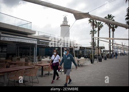 Malaga, Espagne. 05 février 2021. Un couple portant un masque facial passe devant une terrasse vide du restaurant argentin fermé dans une zone commerciale de Malaga.de nombreux magasins, magasins et activités non essentielles qui ont fermé en raison de la troisième vague de pandémie de coronavirus montrent encore des situations vides dans divers endroits de la ville de Malaga, au moins jusqu'au 15 février. Crédit : SOPA Images Limited/Alamy Live News Banque D'Images