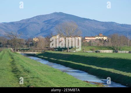 Vue panoramique d'une zone agricole de ​​Tuscany avec un canal d'irrigation et montagnes en arrière-plan Banque D'Images
