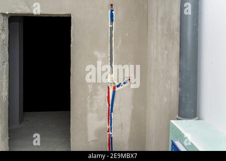 Un robinet en laiton inséré dans le plâtre dans une douche dissimulée, conduits d'eau isolés visibles. Banque D'Images