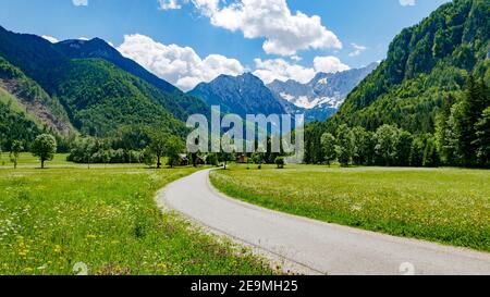 Belle photo d'une route menant à travers les champs verts et montagne Banque D'Images