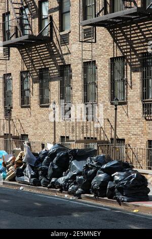 New York - des sacs à ordures ménagères en attente de collecte sur un trottoir de Manhattan. Banque D'Images