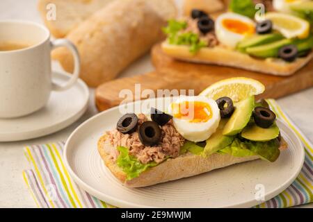 Sandwichs au thon, aux œufs, aux olives et à l'avocat sur fond clair. Banque D'Images