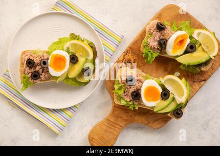 Sandwichs au thon, aux œufs, aux olives et à l'avocat sur fond clair. Banque D'Images