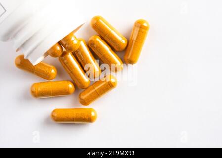 Capsules de racine de curcuma déversées d'une bouteille Banque D'Images