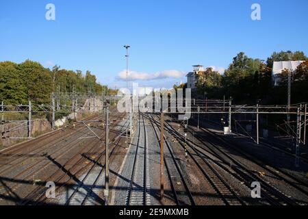 Chemin de fer à Helsinki, Finlande. Photographié sept. 2019. Plusieurs voies de train avec lignes d'alimentation électrique, quelques arbres, ciel bleu et le Mall of Tripla. Banque D'Images