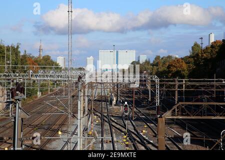 Chemin de fer à Helsinki, Finlande. Photographié sept. 2019. Plusieurs voies de train avec lignes d'alimentation électrique, quelques arbres, ciel bleu et le Mall of Tripla. Banque D'Images