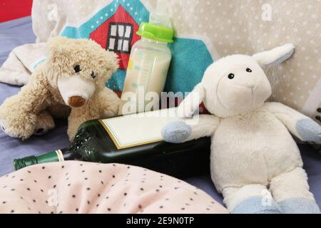 Image symbole de la dépendance à l'alcool chez les parents : jouets en peluche, bouteille pour bébé et alcool Banque D'Images