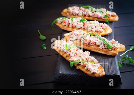 Bruschetta au saumon cuit au four. Tapas. Sandwich avec salsa de saumon, fromage feta, avocat, tomates et oignon rouge. Toasts au saumon riyet. Banque D'Images