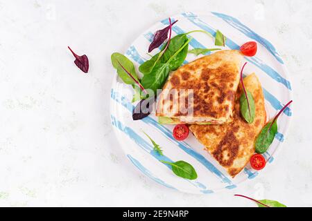 Petit déjeuner savoureux avec quesadilla et œufs. Cuisine mexicaine. Plats tendance avec omelette, fromage, tomates, avocat. Déjeuner simple et facile. Vue de dessus, cop Banque D'Images