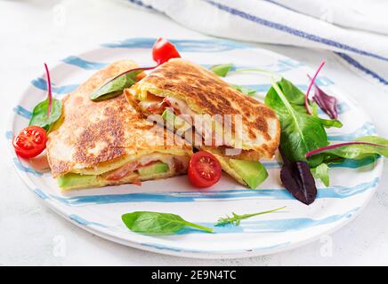 Petit déjeuner savoureux avec quesadilla et œufs. Cuisine mexicaine. Plats tendance avec omelette, fromage, tomates, avocat. Déjeuner simple et facile. Banque D'Images