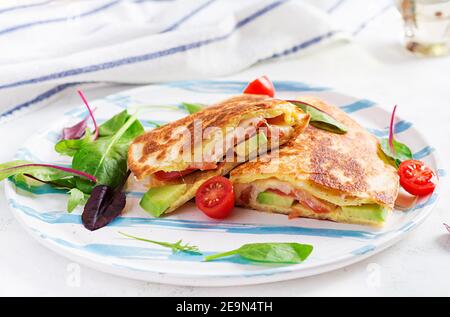 Petit déjeuner savoureux avec quesadilla et œufs. Cuisine mexicaine. Plats tendance avec omelette, fromage, tomates, avocat. Déjeuner simple et facile. Banque D'Images