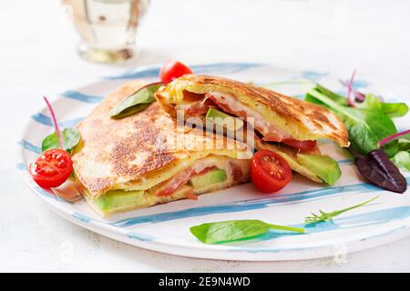 Petit déjeuner savoureux avec quesadilla et œufs. Cuisine mexicaine. Plats tendance avec omelette, fromage, tomates, avocat. Déjeuner simple et facile. Banque D'Images