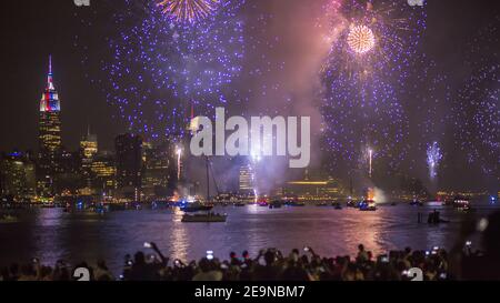 Une foule de personnes prenant des photos de superbes feux d'artifice violets Manhattan Banque D'Images