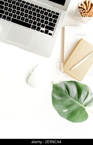 Bureau à la maison avec pose à plat. Espace de travail féminin avec ordinateur portable, feuilles de palmier tropicales Monstera, accessoires sur fond blanc. Vue de dessus de fond féminin Banque D'Images