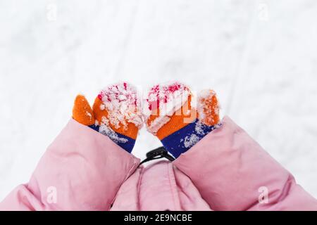 neige sur les moufles ou les gants. Les mains des enfants tiennent les mains dans la neige. Moufles d'hiver tricotées colorées, tachées de neige. Vacances d'hiver. Banque D'Images
