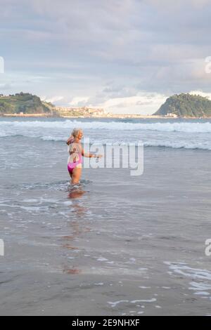 Europe, Espagne, Gipuzkoa, plage de Zarautz avec belle femme plus ancienne se baignant à l'aube Banque D'Images