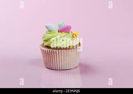 Gâteau de Pâques à la pistache lumineuse avec décorations en gros plan sur le rose arrière-plan Banque D'Images