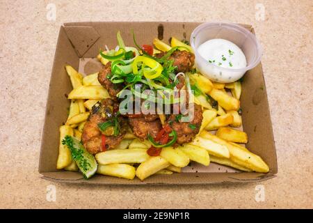 Calmar frit avec des chips de pomme de terre et un côté de sauce Aioli et un coin de lime dans un plateau en carton à emporter Banque D'Images