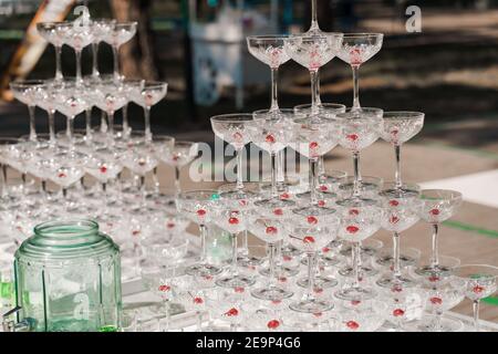 Pyramide de verres avec champagne et cerise rouge à l'intérieur lors d'une réunion d'affaires le jour de l'été. Banque D'Images