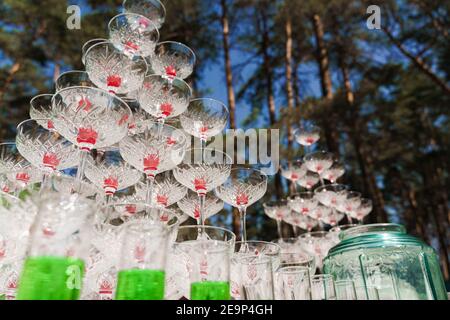 Buvez un cocktail pour votre mariage. Grande pyramide de verres avec champagne et cerise rouge à l'intérieur lors d'une réunion d'affaires le jour d'été dans la forêt. Banque D'Images