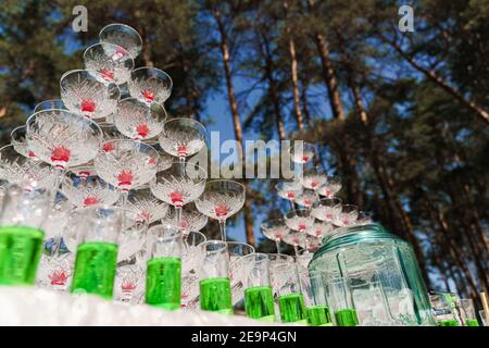 Buvez un cocktail pour votre mariage. Grande pyramide de verres avec champagne et cerise rouge à l'intérieur lors d'une réunion d'affaires le jour d'été dans la forêt. Banque D'Images