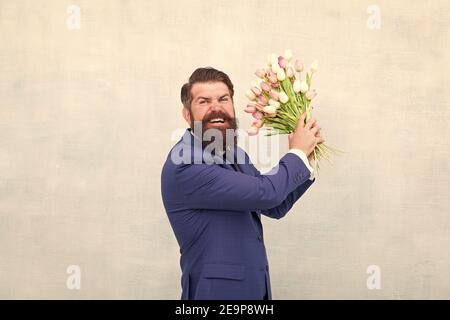 Homme barbu en colère avec des fleurs. Fêtez le printemps. Échec de la date. Irritée, l'homme barbu agacé avec bouquet de tulipes. Concept déçu. Date d'échec. Des vacances de haine. Journée pour femme. 8 Mars. Banque D'Images
