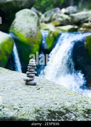 Pyramide de galets équilibrée avec chute d'eau de rivière non focalisée sur le fond Banque D'Images