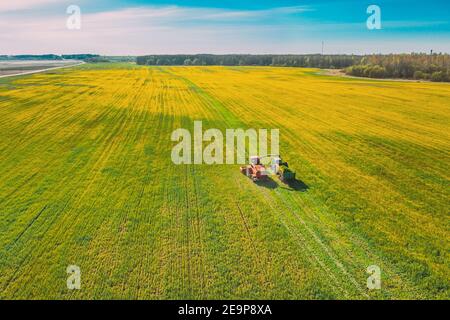 Vue aérienne du paysage rural. Moissonneuse-batteuse et tracteur travaillant ensemble dans les champs. Récolte de graines oléagineuses au printemps. Machines agricoles Banque D'Images