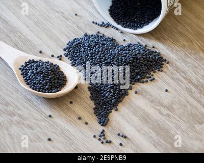 lentilles noires dans une casserole sur une table rustique en bois Banque D'Images