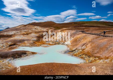 Homme en randonnée au-delà d'un étang géothermique au volcan Krafla in nord de l'Islande Banque D'Images