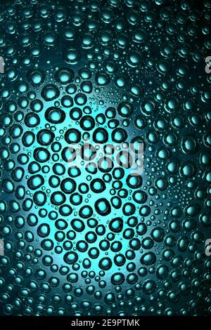 Bulles sur un fond intéressant, disposées de manière chaotique dans l'eau sur la surface en verre Banque D'Images
