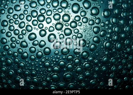 Bulles sur un fond intéressant, disposées de manière chaotique dans l'eau sur la surface en verre Banque D'Images