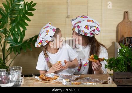 Une conversation de mère et de fille de cinq ans pleine d'amour et d'affection tout en mangeant de la pizza maison. La joie des moments passés ensemble par la mère et la fille tout en mangeant. Banque D'Images