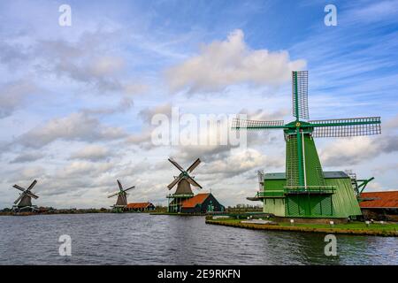 Des moulins à vent verts et des prairies le long du canal par temps clair. Beaux nuages à Zaanse Schans, pays-Bas c'est une destination touristique populaire. Banque D'Images