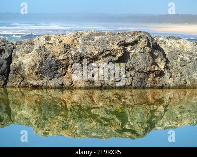 De magnifiques reflets. Les rochers bordant la piscine se réfléchit et se reflétaient dans l'eau salée, en regardant au-delà de l'océan Pacifique Banque D'Images