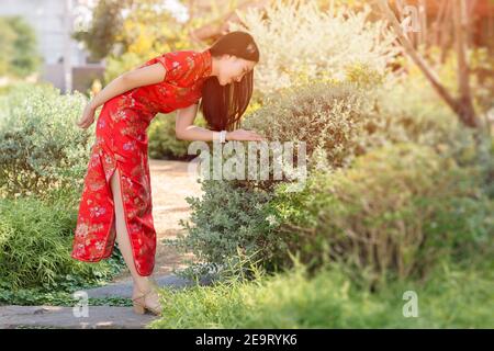 Belle fille chinoise dans le parc vert arrière dressing Qipao traditionnel tissu en chinois nouvel an. Banque D'Images