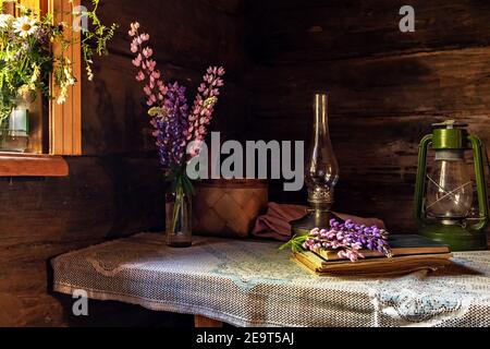 Encore la vie d'articles vintage et un bouquet de lupins sur une table près de la fenêtre dans un vieux village maison Banque D'Images