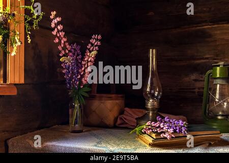 Encore la vie d'articles vintage et un bouquet de lupins sur une table près de la fenêtre dans un vieux village maison Banque D'Images