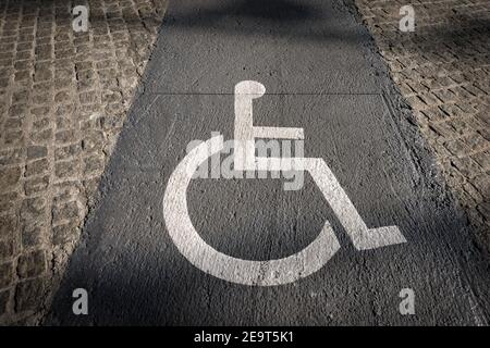 Allée réservée aux fauteuils roulants dans la ville de Barcelone avec un symbole blanc (Accessibilité pour les personnes handicapées) peint sur le béton gris. Banque D'Images