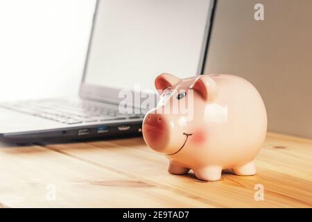Tirelire sur une table en bois avec un ordinateur portable. Concept d'économie d'argent. Banque D'Images