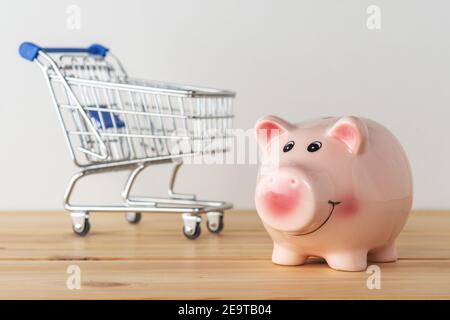 Tirelire sur une table en bois avec un chariot à provisions. Concept d'économie d'argent. Banque D'Images