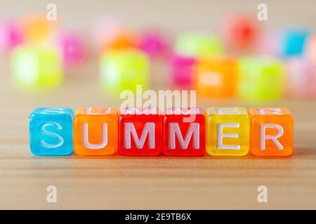 Texte D'ÉTÉ avec des lettres de couleur cubes sur fond en bois. Concept de vacances minimal. Banque D'Images